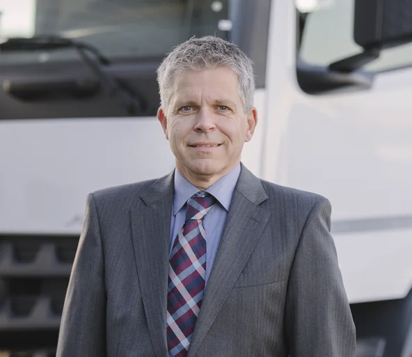Portrait Andreas Böckler vor einem LKW in Anzug