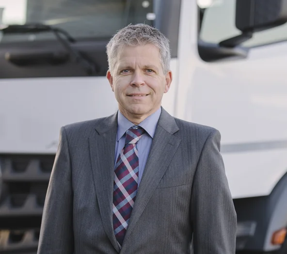 Portrait Andreas Böckler vor einem LKW in Anzug