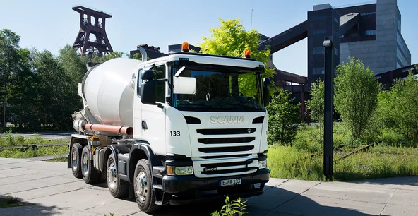Weißer Betonmischer vor Industrieanlage